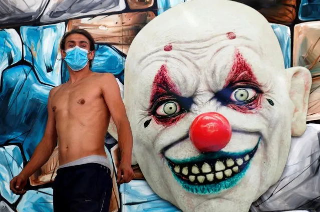 A fairground worker wearing a face mask stands in front of an attraction after the “Midi Fair” was cancelled by local authorities as Belgium tightens measures aimed to contain the spread of the coronavirus, in Brussels, Belgium on July 29, 2020. (Photo by Francois Lenoir/Reuters)