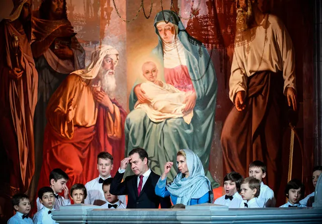 Russian Prime Minister Dmitry Medvedev (C- L) and his wife Svetlana (C- R) attend a Christmas service in Christ the Savior cathedral in Moscow early on January 8, 2018. Orthodox Christians celebrate Christmas on January 7 in the Middle East, Russia and other Orthodox churches that use the old Julian calendar instead of the 17 th- century Gregorian calendar adopted by Catholics, Protestants, Greek Orthodox and commonly used in secular life around the world. (Photo by Alexander Nemenov/AFP Photo)