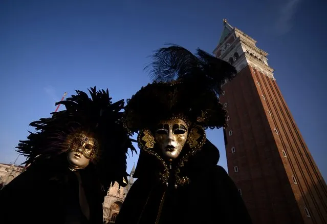 Masked revellers wearing traditional carnival costumes stand in St Mark Square during Venice's Carnival on January 28, 2018. (Photo by Filippo Monteforte/AFP Photo)