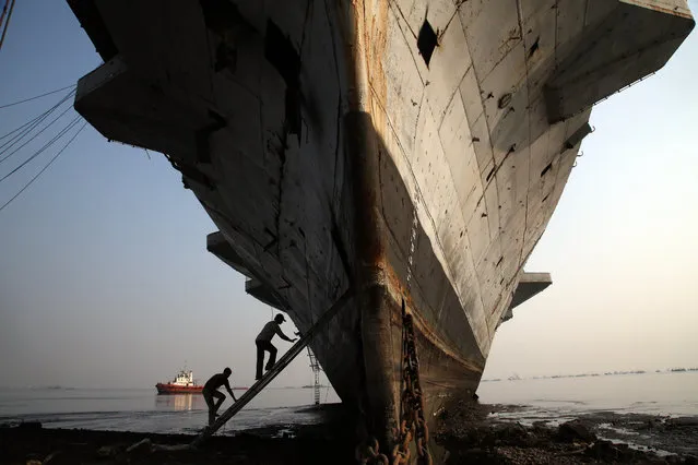 Workers climb to enter India's first aircraft carrier INS Vikrant to dismantle it at a ship-breaking yard in Mumbai, India, Saturday, November 22, 2014. The iconic naval vessel, that was purchased from Britain in 1957, played a key role during the India-Pakistan war of 1971 and was decommissioned in 1997. (Photo by Rajanish Kakade/AP Photo)