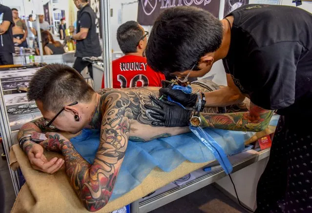 A man uses his mobile phone as he gets a tattoo at the China TATTOO convention in Nanning, Guangxi Zhuang Autonomous Region, China, October 24, 2015. (Photo by Reuters/Stringer)