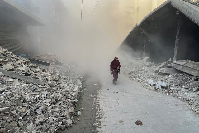 A Palestinian young woman rushes away from the site of Israeli air strikes on a six-storey building in the Saftawi neighborhood west of Jabalia in the northern Gaza Strip on August 19, 2025. Gaza's civil defence agency reported that 45 people were killed on August 19 by Israeli strikes and fire across the territory. (Photo by Bashar Taleb/AFP Photo)