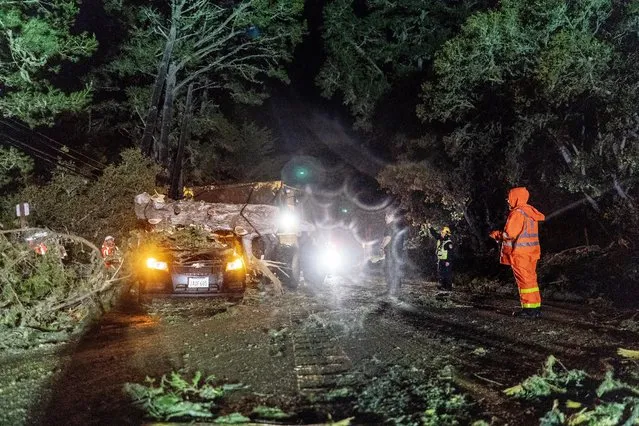CalFire and CalTrans crews work to remove large trees fallen across Highway 1 crushing a car and stopping traffic during high winds and heavy rain caused by an atmospheric river slamming California in Carmel, California on Thursday March 9, 2023. (Melina Mara/The Washington Post)