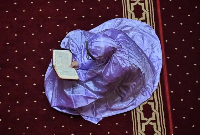 A Muslim woman reads a copy of the Koran on the fourth day of the holy month of Ramadan at the Istiqlal mosque in Jakarta on March 26, 2023. (Photo by Adek Berry/AFP Photo)