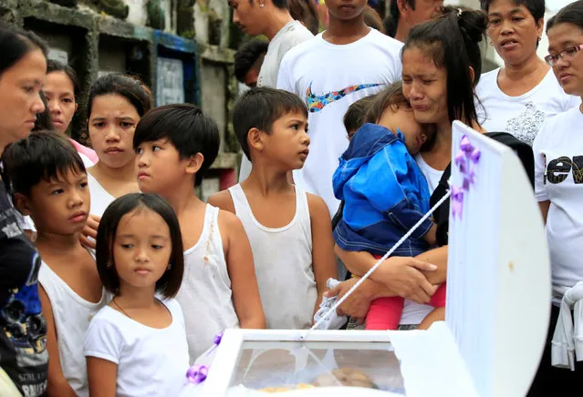 Loved ones and friends gather in front of the coffin to view the body of Apolinario Eyana Jr., who was killed by unidentified men, during his burial rites inside the public cemetery in Navotas city, metro Manila, Philippines October 16, 2016. (Photo by Romeo Ranoco/Reuters)