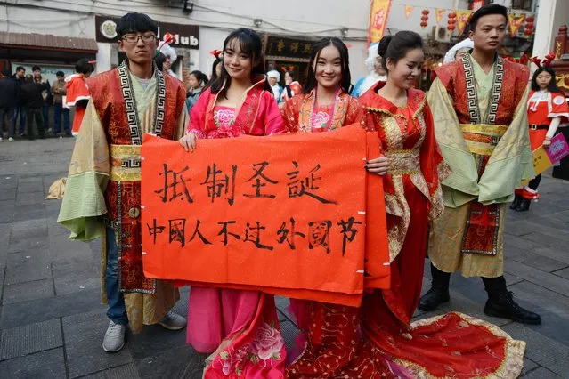 This picture taken on December 24, 2014 shows university students wearing traditional Chinese outfits holding banners reading “Resist Christmas, Chinese people should not celebrate foreign festivals” in Changsha, central China's Hunan province during an anti-Christmas street protest. (Photo by AFP Photo)