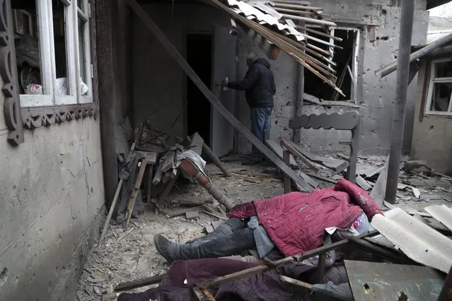 A body of woman, killed during shelling, lies under debris of a damaged house in Donetsk, in the territory controlled by pro-Russian militants, eastern Ukraine, Friday, February 25, 2022. The Russian military is pressing its invasion of Ukraine to the outskirts of the capital. The advancement came after Russia unleashed airstrikes on cities and military bases and sent in troops and tanks from three sides in an attack that could rewrite the global post-Cold War security order. (Photo by Alexei Alexandrov/AP Photo)