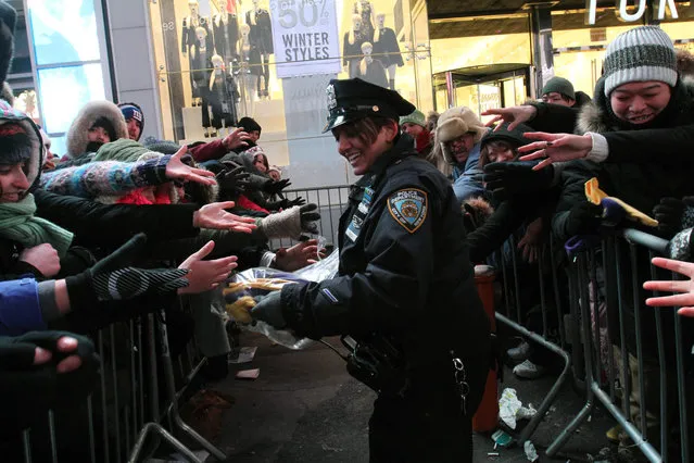 NYPD police officer Bedi, center, distributes gloves, given to her by the Time Square Alliance, to revelers in New York's Times Square during the New Year's Eve festivities Wednesday, December 31, 2014. (Photo by Tina Fineberg/AP Photo)