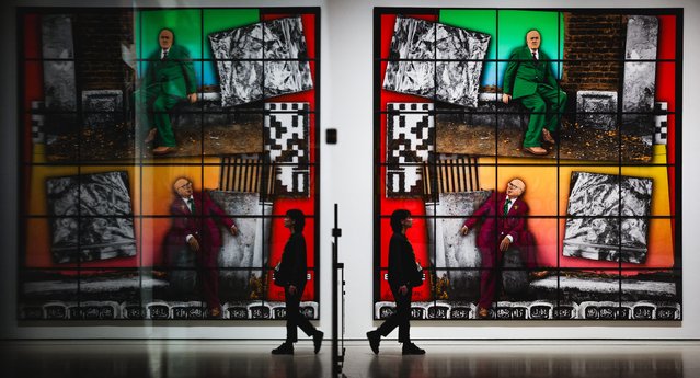 An assistant poses in front of the Gilbert & George 2020 work entitled “Bagrave” during a photo call for the exhibition “Gilbert & George: 21st Century Pictures” at the Hayward Gallery in London on October 6, 2025. (Photo by Adrian Dennis/AFP Photo)