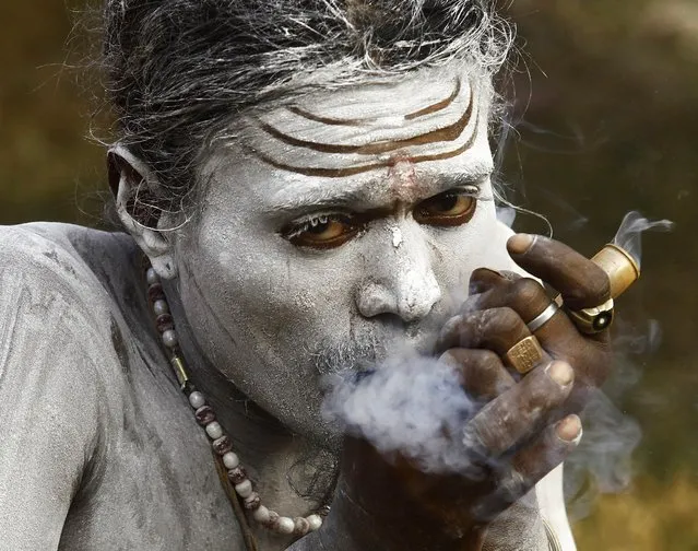 A Sadhu or a Hindu holy man, smokes cannabis inside a makeshift shelter on the banks of river Ganges, on his way to an annual trip to Sagar Island, in Kolkata January 8, 2015. Hindu monks and pilgrims are making the annual trip to Sagar Island for a holy dip at the confluence of the Ganges river and the Bay of Bengal on January 14. (Photo by Rupak De Chowdhuri/Reuters)