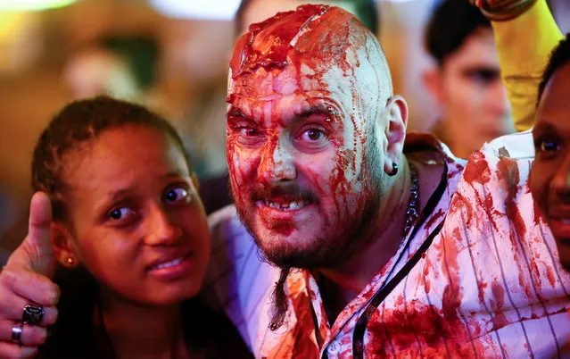 A tourist poses with a man dressed as a zombie during the so-called “Zombie walk” through the western German city of Essen on Halloween Day, October 31, 2016. (Photo by Wolfgang Rattay/Reuters)