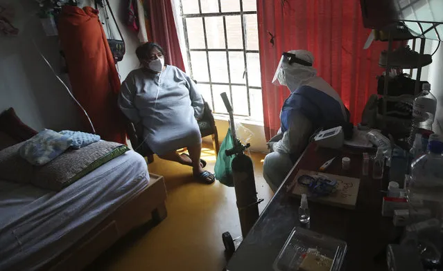 City worker Carlos Ruiz gives instruction to a COVID-19 patient after delivering a tank of oxygen to her home in the Iztapalapa borough of Mexico City, Friday, January 15, 2021. The city offers free oxygen refills for COVID-19 patients. (Photo by Marco Ugarte/AP Photo)
