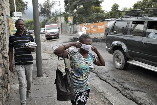 A woman walks past local authorities removing the bodies of men that were set on fire by a mob in Port-au-Prince, Haiti, Tuesday, April 25, 2023, a day after a mob pulled the 13 suspected gang members from police custody at a traffic stop and beat and burned them to death with gasoline-soaked tires. (Photo by Joseph Odelyn/AP Photo)