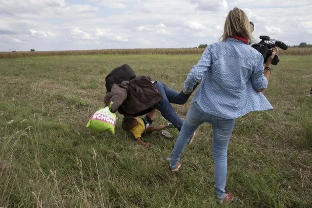 A migrant carrying a child falls after tripping on TV camerawoman (R) Petra Laszlo while trying to escape from a collection point in Roszke village, Hungary, September 8, 2015. (Photo by Marko Djurica/Reuters)