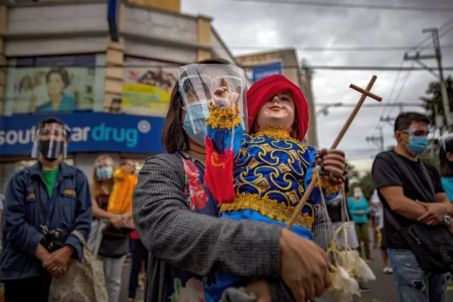 A devotee wearing a facemask and face shield to protect against COVID-19 carries a statue of Baby Jesus (known locally as “Santo Nino”) as she attends a mass outside a church in celebration of the Feast of Santo Nino on January 17, 2021 in Manila, Philippines. Authorities have prohibited most festivities in celebration of the Feast of Santo Nino but have allowed physical masses amid concerns that the event could help spread the coronavirus disease. (Photo by Ezra Acayan/Getty Images)
