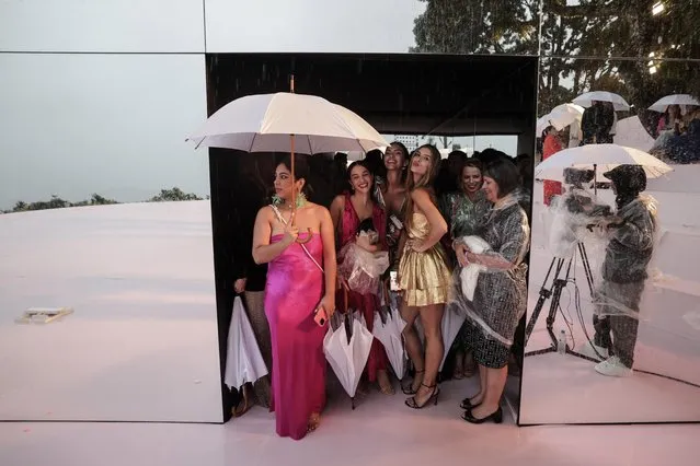 Guests for the Carolina Herrera parade take shelter from the rain in Rio de Janeiro, Brazil on June 1, 2023.The American firm Carolina Herrera held its first fashion show outside of New York with a collection inspired by the energy and joy of Rio. The show went on but without an audience. (Photo by Antonio Lacerda/EPA/EFE)