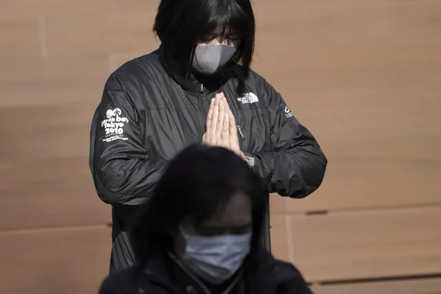 A staff member mourns for the victims of the 2011 earthquake and tsunami during an online special memorial event at Hibiya Park in Tokyo Thursday, March 11, 2021. Japan on Thursday marked the 10th anniversary of the massive earthquake, tsunami and nuclear disaster that struck Japan's northeastern coast. (Photo by Eugene Hoshiko/AP Photo)