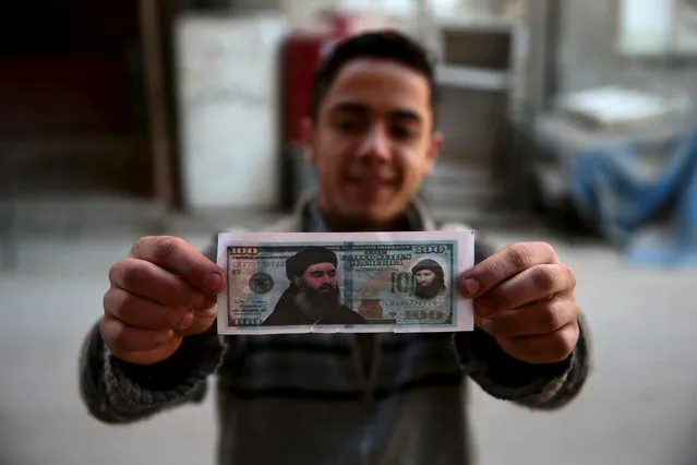 A boy poses while showing one of the fake U.S. 100 dollar banknotes depicting Islamic State's leader Abu Bakr al-Baghdadi (L) and al-Nusra Front's leader Abu Mohammed al-Joulani (R), that were dropped by Syrian army jets in the Douma neighborhood of Damascus, Syria December 27, 2015. (Photo by Bassam Khabieh/Reuters)