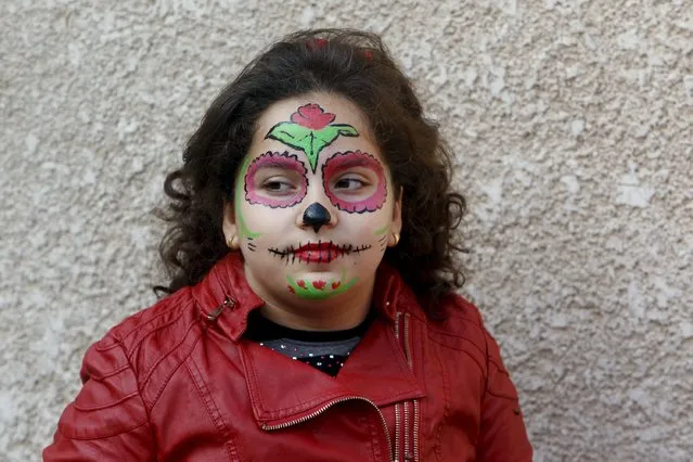 An internally displaced Christian girl, who has fled from Islamic State militants, stands against a wall with her face painted, at a church in Baghdad November 20, 2015. (Photo by Khalid al-Mousily/Reuters)