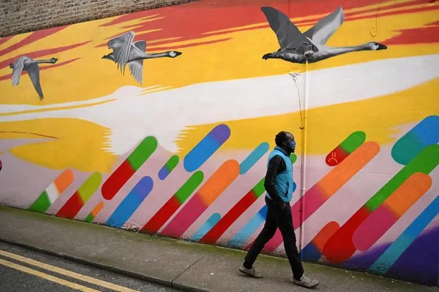 A man wearing a protective face mask walks past a painted wall, amid the coronavirus disease (COVID-19) outbreak in Dublin, Ireland on February 24, 2021. (Photo by Clodagh Kilcoyne/Reuters)