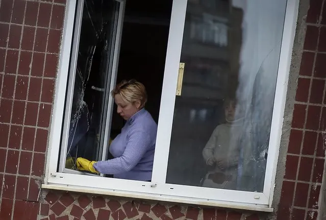 A woman removes glass from the broken window of her home in the town of Kramatorsk, eastern Ukraine February 10, 2015. (Photo by Gleb Garanich/Reuters)
