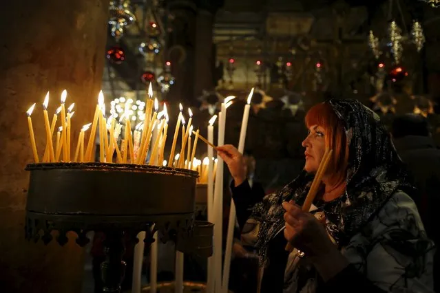 A worshipper lights candles as she attends a Christmas service according to the Eastern Orthodox calendar, in the church of Nativity in the West Bank city of Bethlehem January 6, 2016. (Photo by Ammar Awad/Reuters)