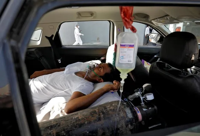 A patient with breathing problems lies inside a car while waiting to enter a COVID-19 hospital for treatment, amidst the spread of the coronavirus disease (COVID-19), in Ahmedabad, India, April 22, 2021. (Photo by Amit Dave/Reuters)