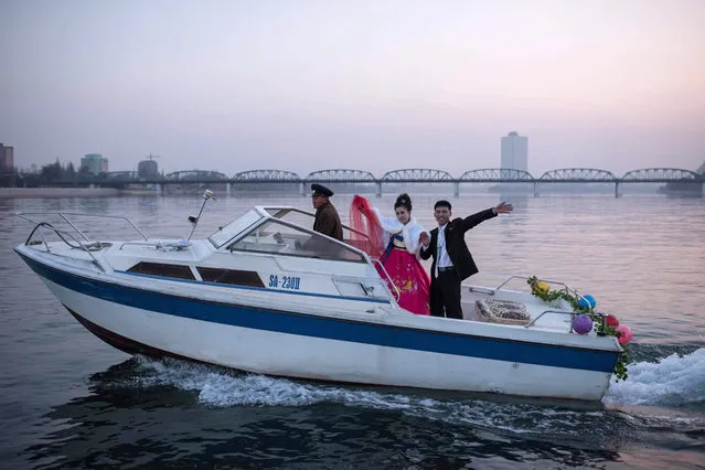 A bride and groom wave as they pose for their wedding photos aboard a boat on the Taedong river in Pyongyang on November 25, 2016. (Photo by Ed Jones/AFP Photo)