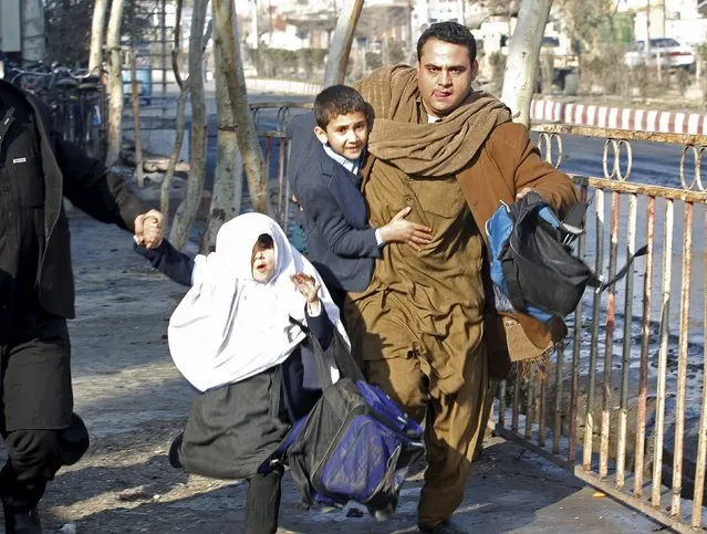 A man carries his son as they run after a blast near the Pakistani consulate in Jalalabad, Afghanistan January 13, 2016. (Photo by Reuters/Parwiz)