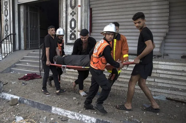 Palestinian rescuers evacuate an elderly woman from a building following Israeli airstrikes on Gaza City, Wednesday, May 12, 2021. Rockets streamed out of Gaza and Israel pounded the territory with airstrikes early Wednesday as the most severe outbreak of violence since the 2014 war took on many of the hallmarks of that devastating 50-day conflict, with no endgame in sight. (Photo by Khalil Hamra/AP Photo)