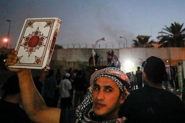A supporter of Iraqi Shiite cleric Moqtada al-Sadr holds a copy of the Koran, Islam's holy book, as he and others gather for a protest outside the Swedish embassy in Baghdad on July 20, 2023. Protesters set fire to Sweden's embassy in the Iraqi capital early on July 20 ahead of a planned burning of a Koran in Sweden. Swedish authorities approved an assembly to be held later on July 20 outside the Iraqi embassy in Stockholm, where organisers plan to burn a copy of the Koran as well as an Iraqi flag. (Photo by AAhmad Al-Rubaye/AFP Photo)