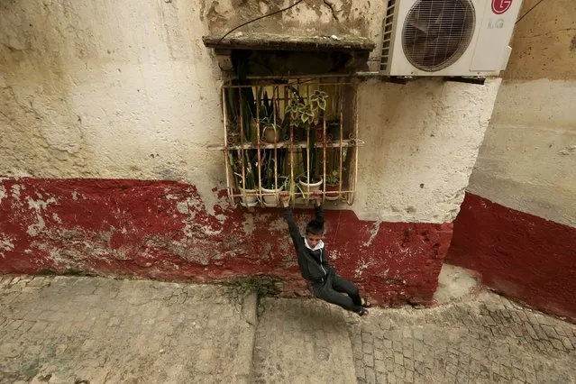 A boy swings on window bars in the old city of Algiers Al Casbah, Algeria December 3, 2015. (Photo by Zohra Bensemra/Reuters)