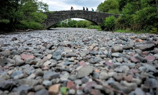 People cross a bridge over the dry river bed of the River Derwent after a prolonged period of dry weather in Grange, Britain on June 18, 2023. (Photo by Phil Noble/Reuters)