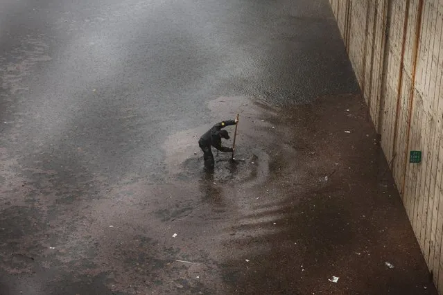 A person tries to unclog a drain grate along a flooded Prospect Expressway after it got stuck in high water during heavy rain and flooding on September 29, 2023 in the Brooklyn Borough of New York City. Much of the Northeast is experiencing severe flooding after heavy rains swept through the area this morning. (Photo by Spencer Platt/Getty Images)