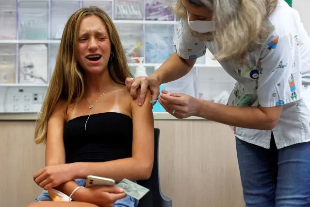 A teenager reacts while receiving a dose of a vaccine against the coronavirus disease (COVID-19) as Israel urged more 12- to 15-year-olds to be vaccinated, citing new outbreaks attributed to the more infectious Delta variant, at a Clalit healthcare maintenance organisation in Tel Aviv, Israel on June 21, 2021. (Photo by Amir Cohen/Reuters)