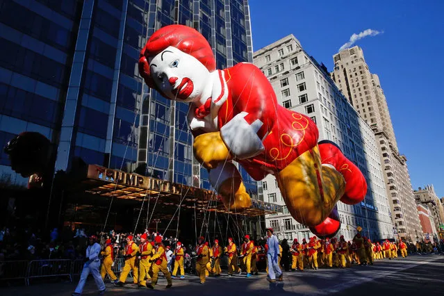 The Ronald McDonald balloon passes by windows of a building on Central Park West during the 92nd annual Macy's Thanksgiving Day Parade in New York, Thursday, November 22, 2018. (Photo by Eduardo Munoz Alvarez/AP Photo)