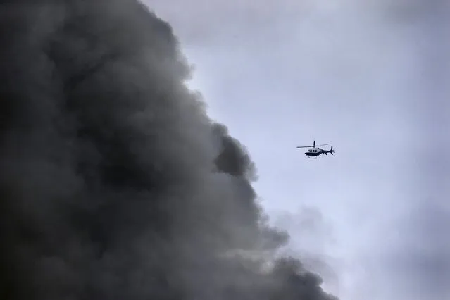 A New York City Police helicopter flies near billowing smoke above the site of a residential apartment building collapse and fire in New York City's East Village neighborhood March 26, 2015. (Photo by Brendan McDermid/Reuters)