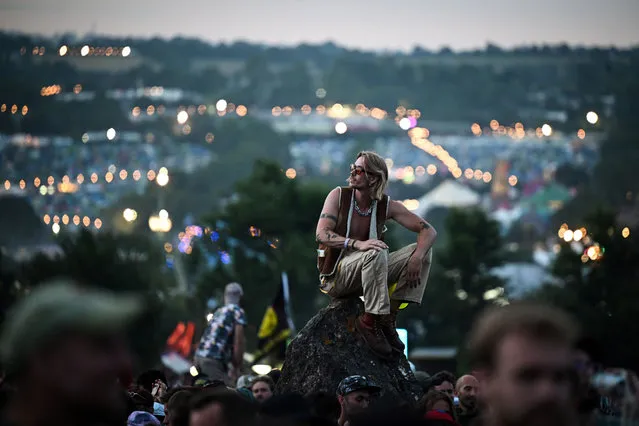 A festival goer watches the sunset from the Stone Circle on the first day of the Glastonbury festival in the village of Pilton, in Somerset, southwest England, on June 21, 2023. The festival takes place from June 21 to June 26. (Photo by Oli Scarff/AFP Photo)
