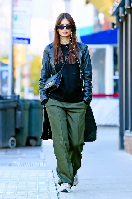 Emily Ratajkowski is pictured stepping out in New York City on October 13, 2023. The American supermodel wore a black trench coat, green trousers, and grey trainers. (Photo by The Image Direct)