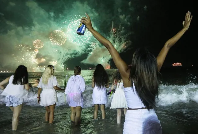 Revelers celebrate during fireworks marking the start of the New Year on Copacabana beach on January 1, 2017 in Rio de Janeiro, Brazil. Brazilian revelers traditionally dress in white to honor the New Year's holiday along with the Brazilian Goddess of the Sea- Iemanja. (Photo by Mario Tama/Getty Images)