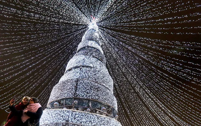People take a photo near an illuminated New Year tree in the downtown of Minsk, Belarus, 27 December 2018. (Photo by Tatyana Zenkovich/EPA/EFE)