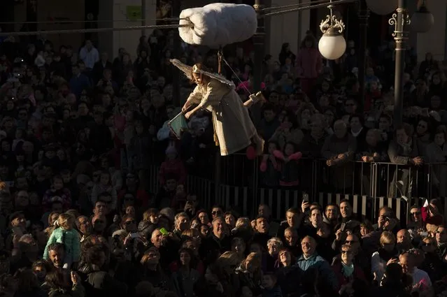 Eight-year-old Alba Oroz, secured by a harness, is transported in the air, above the crowd as she unveils the face of a statue of the Virgin Mary, during the Easter Sunday ceremony “Descent of the Angel”, during Holy Week in the small town of Tudela, northern Spain, Sunday, April 5, 2015. (Photo by Alvaro Barrientos/AP Photo)