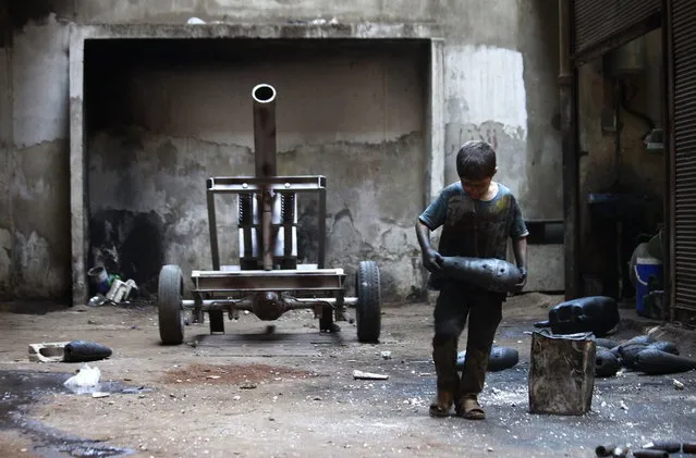 Issa, 10 years old, carries a mortar shell in a weapons factory of the Free Syrian Army in Aleppo, September 7, 2013. Issa works with his father in the factory for ten hours every day except on Fridays. (Photo by Hamid Khatib/Reuters)