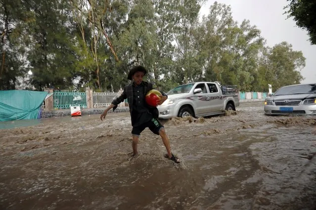 A Yemeni boy wades and attempts to traverse a flooded street following heavy rainfall in Sana'a, Yemen, 23 July 2021. Heavy rainfall and a​ssociated floods have hit several cities of Yemen over the past few days. (Photo by Yahya Arhab/EPA/EFE)