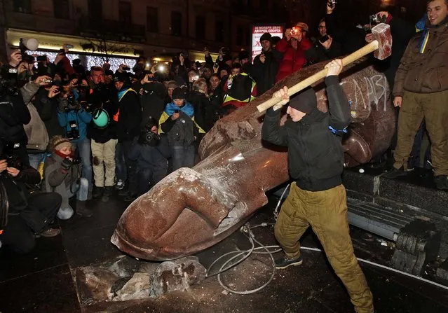 An anti-government protester beats a statue of Vladimir Lenin with a sledgehammer in Kiev, Ukraine, on December 8, 2013. (Photo by Sergei Chuzavkov/Associated Press)