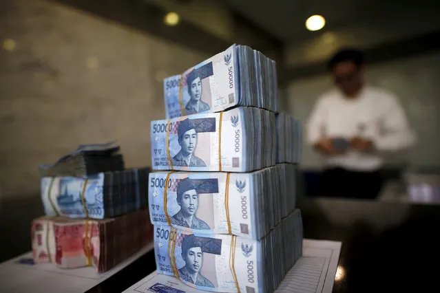A teller in Bank Indonesia's headquarters counts rupiah bank notes in Jakarta, Indonesia April 21, 2016. (Photo by Darren Whiteside/Reuters)