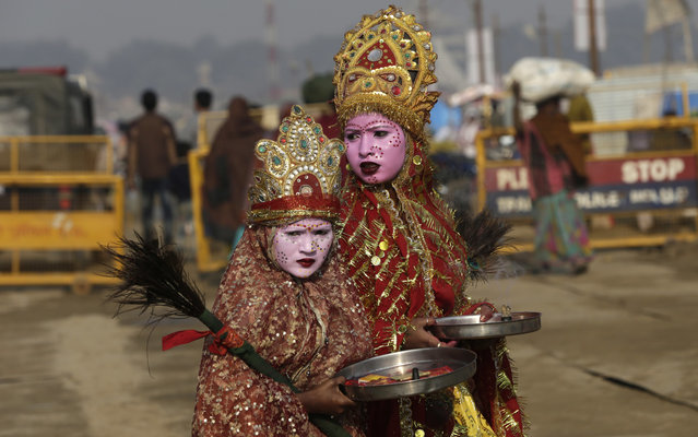 Siblings stand dressed as river goddesses to attract alms from devotees at “Sangam”, the meeting point of Indian holy rivers the Ganges and the Yamuna on the auspicious day of “Paush Purnima” during the annual traditional fair of Magh Mela in Allahabad, India, Thursday, January 12, 2017. Hundreds of thousands of devout Hindus are expected to take holy dips at the confluence during the astronomically auspicious period of over 45 days celebrated as Magh Mela. (Photo by Rajesh Kumar Singh/AP Photo)