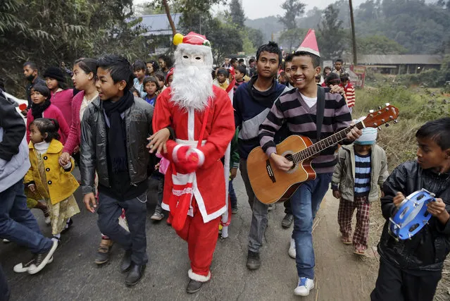 Indian people sing as they walk with a man dressed as Santa Claus ahead of Christmas in Umsning, in Meghalaya, India, Tuesday, December 24, 2013. Though Hindus and Muslims comprise the majority of the population in India, Christmas is celebrated with much fanfare. (Photo by Anupam Nath/AP Photo)