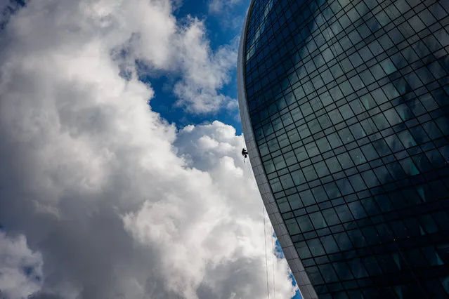 A worker cleans the windows and the facade of the an office building in the Moscow's International Business Centre (Moskva City) on August 23, 2021. (Photo by Dimitar Dilkoff/AFP Photo)