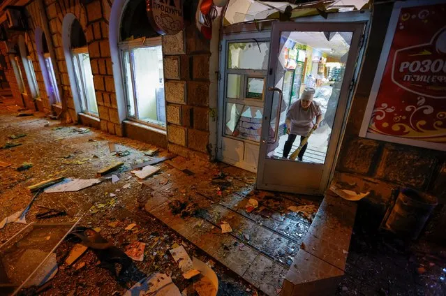 An employee of a grocery store removes debris in a residential building damaged in shelling in the course of Russia-Ukraine conflict in Donetsk, Russian-controlled Ukraine on December 2, 2022. (Photo by Alexander Ermochenko/Reuters)